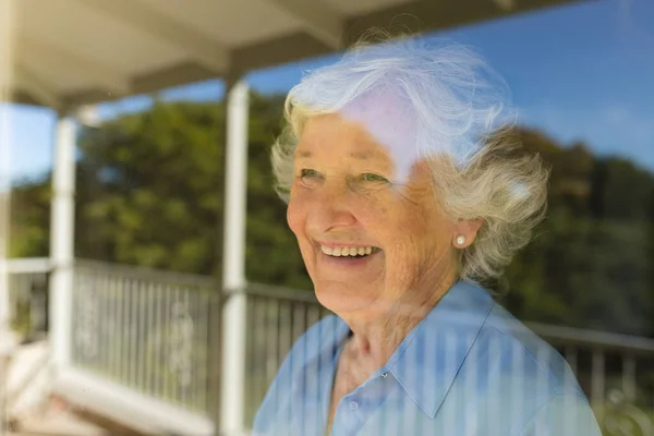 ウィンドウと笑顔を通して見てシニア白人女性 隠遁と退職と幸せなシニアライフスタイルのコンセプト — ストック写真