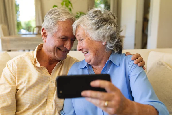 资深的高加索夫妇坐在沙发上 用智能手机进行视频通话 退休和快乐的老年生活方式概念 — 图库照片