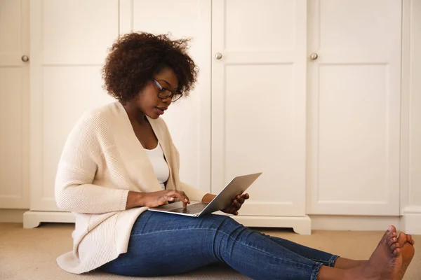 快乐的非洲裔美国女人在卧室里工作 坐在地板上 使用笔记本电脑 灵活的在家工作 — 图库照片