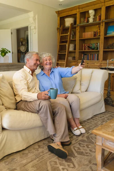 코카서스 부부는 스마트폰으로 비디오 통화를 하면서 소파에 있습니다 노인의 — 스톡 사진