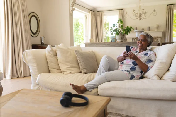 Afrikanische Seniorin Sitzt Mit Smartphone Auf Sofa Und Lächelt Rückzug — Stockfoto