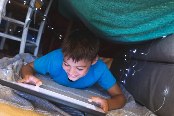 Kaukázusi Fiú Mosolyog Egy Takaróerődben Fekszik Tabletet Használva Otthon Gyermekkor — Stock Fotó