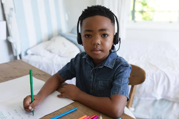 アフリカ系アメリカ人の少年は 自宅でヘッドフォンをしてビデオ通話レッスンを受けています オンライン教育家庭で学ぶこと — ストック写真