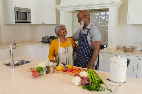 シニアアフリカ系アメリカ人の夫婦がキッチンで一緒に調理する笑顔 隠遁と退職と幸せなシニアライフスタイルのコンセプト — ストック写真