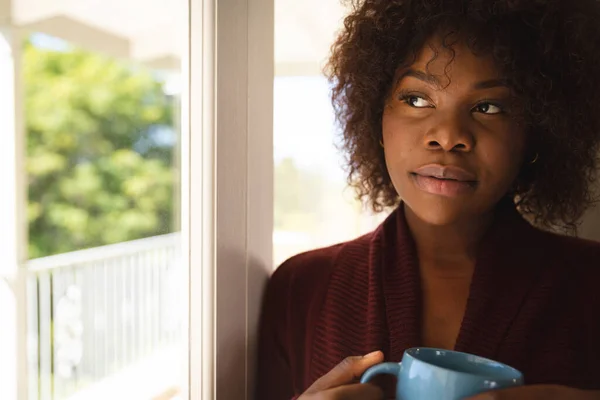 Pensativa Mujer Afroamericana Mirando Por Ventana Soleada Sosteniendo Una Taza —  Fotos de Stock