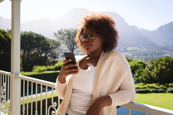 Szczęśliwa Afroamerykanka Stojąca Słonecznym Balkonie Wiejskiego Domu Pomocą Smartfona Styl — Zdjęcie stockowe