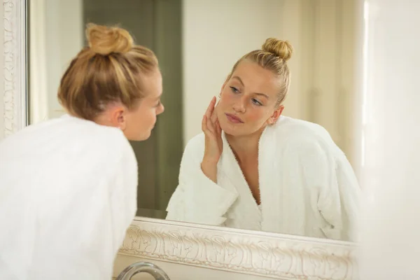 浴室里的白人女人穿着浴衣 照镜子 面容湿润 美丽和幸福 在家里度过高质量的时光 — 图库照片