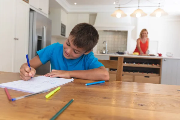 台所の白人の母親と息子は家で笑顔で宿題をしている 家庭内生活や家での時間学習 — ストック写真