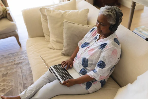 Senior African American Woman Sitting Sofa Wearing Headphones Using Laptop — Stock Photo, Image