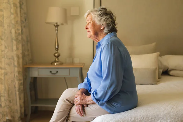 年长的高加索女人坐在床上 在卧室里思考 退休和老年生活方式概念 — 图库照片