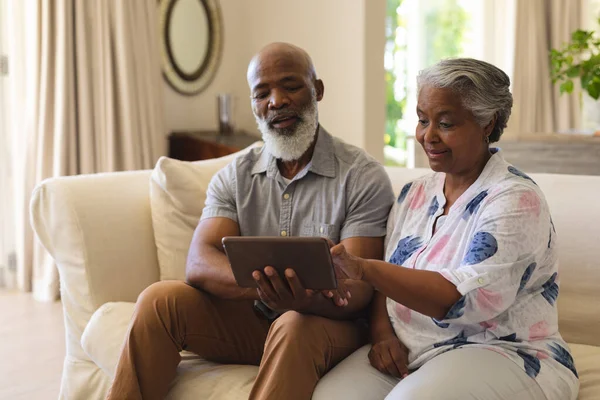 Sênior Casal Afro Americano Sentado Sofá Usando Tablet Sorrindo Retiro — Fotografia de Stock