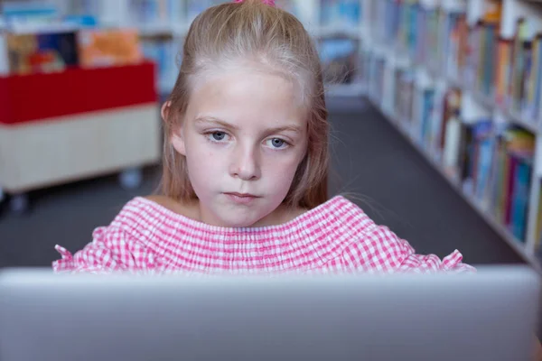 在学校图书馆的书桌前 一个白人女学生用笔记本电脑专心致志 小学的儿童 技术和教育 — 图库照片