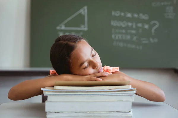 累坏了的混血女学生坐在教室的课桌前 睡在一堆书上 儿童与小学教育 — 图库照片