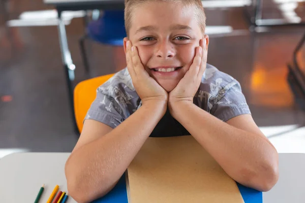 Щасливий Білий Школяр Сидить Столом Класі Спираючись Книги Посміхаючись Дитинство — стокове фото