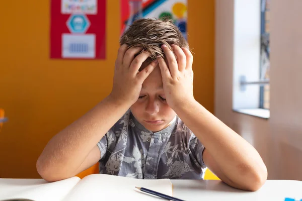 Confused Caucasian Schoolboy Sitting Desk Classroom Books Holding Head Hands — Stock Photo, Image