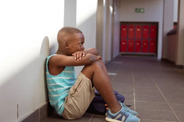 Écolier Afro Américain Bouleversé Assis Sur Sol Dans Couloir École — Photo