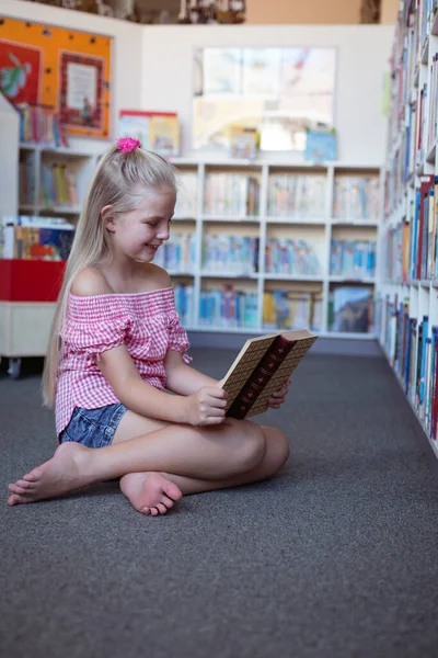 Uśmiechnięta Uczennica Siedząca Podłodze Czytająca Książki Szkolnej Bibliotece Dzieciństwo Edukacja — Zdjęcie stockowe