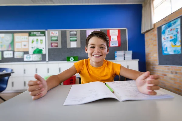 小学生の時に机の上に座りながら笑顔で笑う白人少年の姿が描かれている 学校や教育の概念 — ストック写真