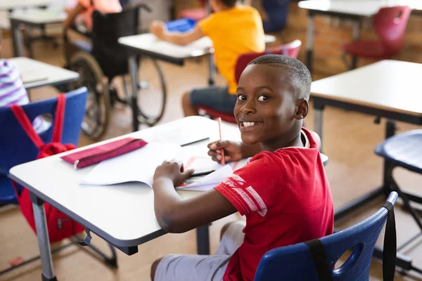 小学生の時に机の上に座っていたアフリカ系アメリカ人の少年の笑顔が描かれている 学校や教育の概念 — ストック写真