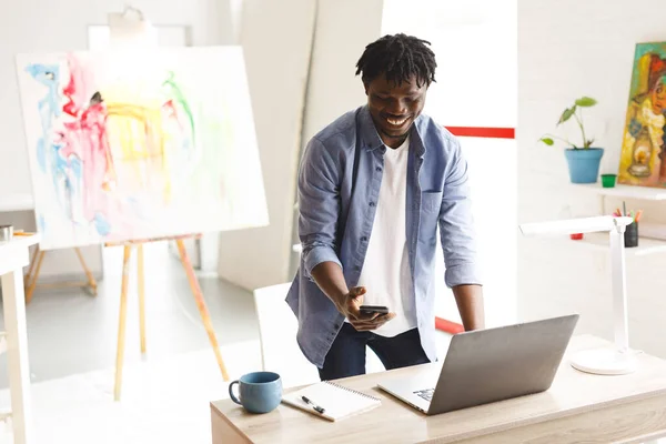 Afrikanischer Maler Bei Der Arbeit Mit Laptop Und Smartphone Kunstatelier — Stockfoto