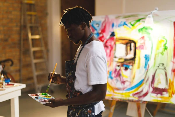 Afrikai Amerikai Férfi Festő Munkahelyén Festékkel Ecsettel Kezében Művészeti Stúdióban — Stock Fotó