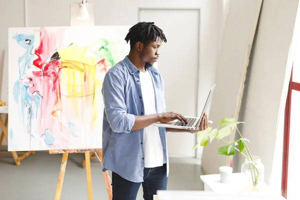 非洲裔美国男性画家在艺术工作室使用笔记本电脑 艺术家绘画工作室的创作和灵感 — 图库照片