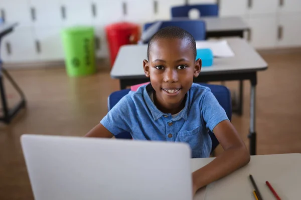 Retrato Niño Afroamericano Sonriendo Mientras Usa Portátil Sentado Escritorio Escuela —  Fotos de Stock