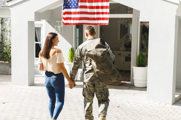 アメリカ国旗で飾られた家の外で妻と手を携えている白人男性兵士 兵士が帰ってきて — ストック写真