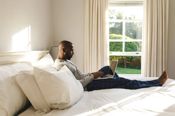 Afro Amerikaanse Man Met Laptop Liggend Bed Zijn Slaapkamer Tijd — Stockfoto