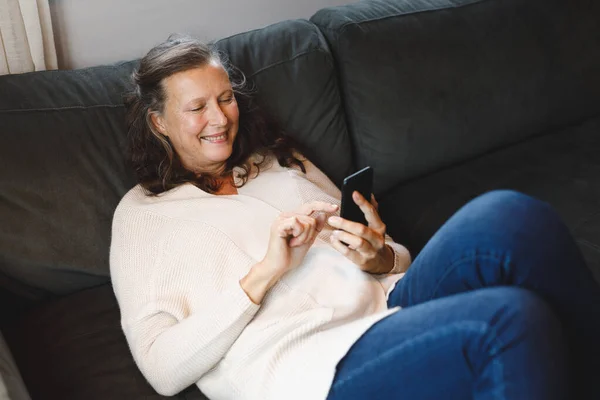 Glad Senior Kaukasiska Kvinna Vardagsrummet Sitter Soffan Med Hjälp Smartphone — Stockfoto