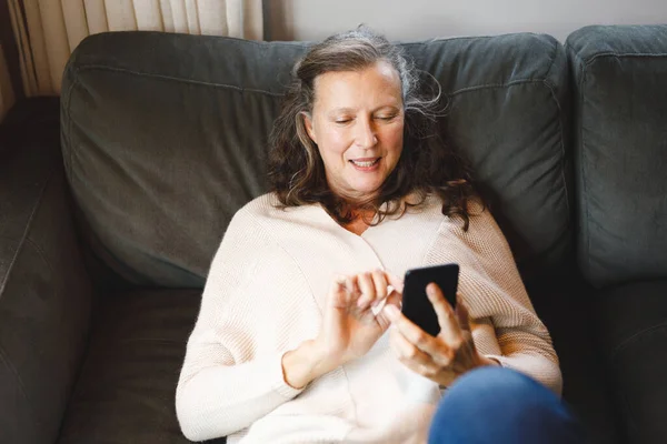 Happy Senior Caucasian Woman Living Room Sitting Sofa Using Smartphone — Stock Photo, Image