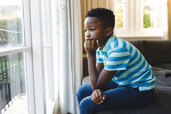 Eftertänksam Afrikansk Amerikansk Pojke Som Sitter Och Tittar Genom Fönstret — Stockfoto