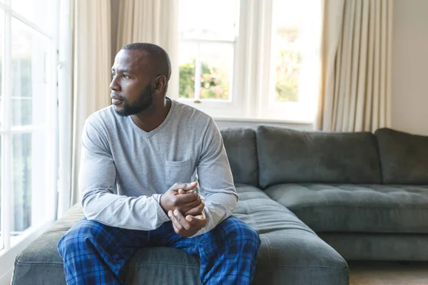 Réfléchi Homme Afro Américain Assis Sur Canapé Regardant Par Fenêtre — Photo