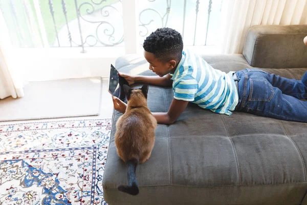 Niño Afroamericano Usando Tableta Acostado Sofá Con Gato Sala Estar — Foto de Stock