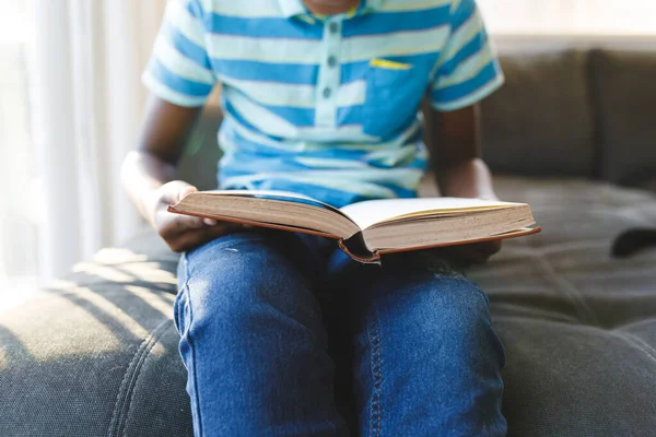 Afrika Kökenli Amerikalı Bir Çocuğun Kitap Okuyup Oturma Odasında Kanepede — Stok fotoğraf