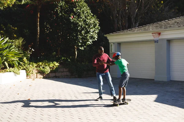 Afroamerikanischer Vater Lächelt Und Hilft Sohn Beim Balancieren Auf Skateboard — Stockfoto