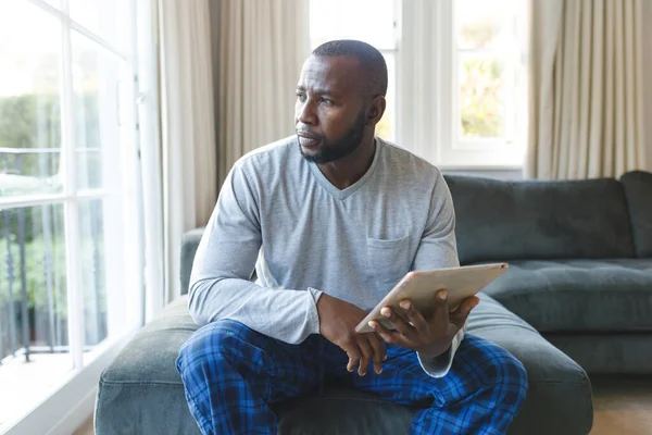 Homme Afro Américain Réfléchi Utilisant Une Tablette Assis Sur Canapé — Photo