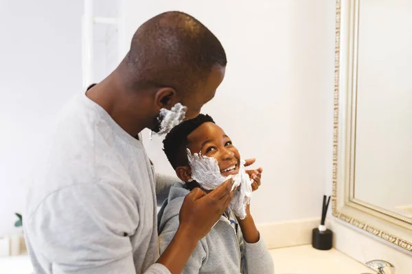 黑人父亲和儿子在浴室里享受刮胡子泡沫的乐趣 家庭呆在家里的时间 — 图库照片
