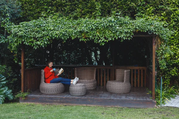幸せなシニア白人女性の椅子に座って 読書や庭でコーヒーを飲む 家で一人で過ごす退職生活や — ストック写真