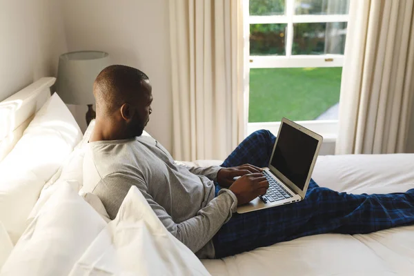 Homem Afro Americano Usando Laptop Deitado Cama Seu Quarto Passar — Fotografia de Stock