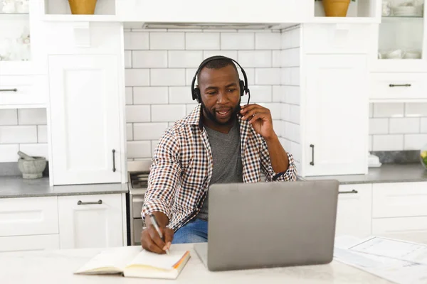 Afrykański Amerykanin Siedzący Kuchni Wykonujący Wideo Rozmowy Pomocą Laptopa Słuchawki — Zdjęcie stockowe