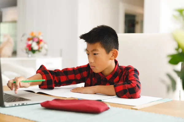 亚洲男孩坐在桌旁 在网上上课时使用笔记本电脑 在家里使用技术的童年 教育和发现 — 图库照片