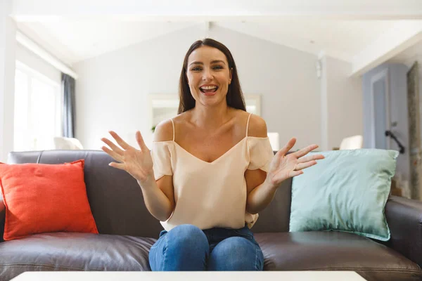 快乐的高加索女人坐在沙发上 在客厅里有视频通话 说话和做手势 与他人保持联系 利用通信技术在家中消闲 — 图库照片