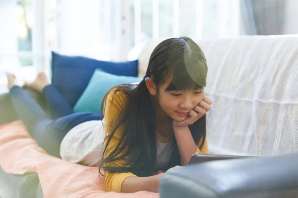 Sorrindo Menina Asiática Deitada Sofá Sala Estar Usando Tablet Tempo — Fotografia de Stock