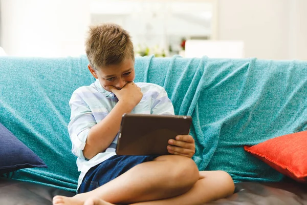 Lachende Blanke Jongen Zittend Bank Tablet Gebruikend Woonkamer Kindervrije Tijd — Stockfoto