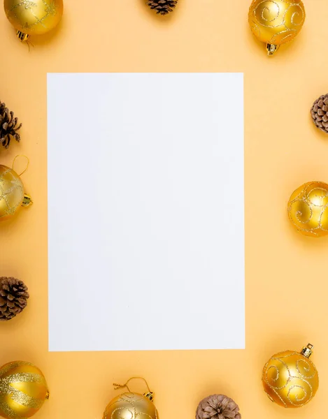 黄色の背景に泡や松のコーンで囲まれたコピースペースとホワイトカードの構成 クリスマス お祝いのコンセプト — ストック写真