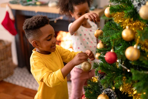 幸せなアフリカ系アメリカ人の兄弟は クリスマスツリーを飾る 赤ちゃんをぶら下げている 家庭での子供時代クリスマス祭り伝統 — ストック写真