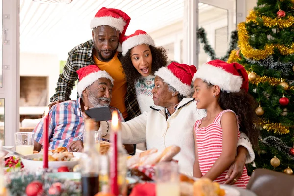 サンタの帽子をかぶった幸せなマルチ世代の家族は 自撮りを取る クリスマスの時間と祭りを一緒に家で — ストック写真