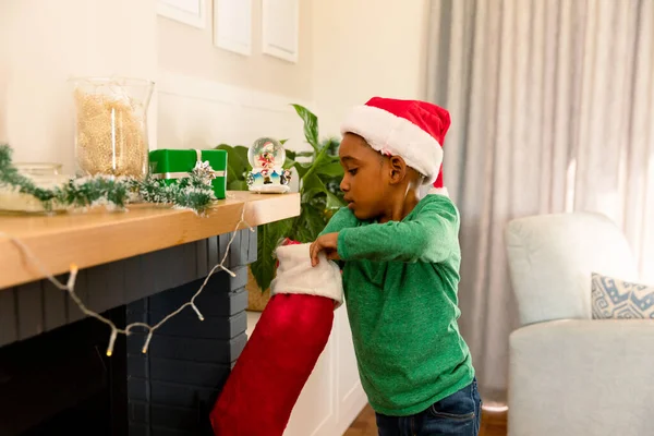 Niño Afroamericano Vistiendo Sombrero Santa Buscando Regalo Medias Navidad Infancia —  Fotos de Stock