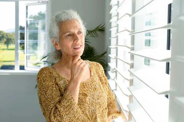 思考の原因アジアの高齢者の女性のウィンドウでは 距離を探して立っている 家庭での健康的な退職生活 — ストック写真